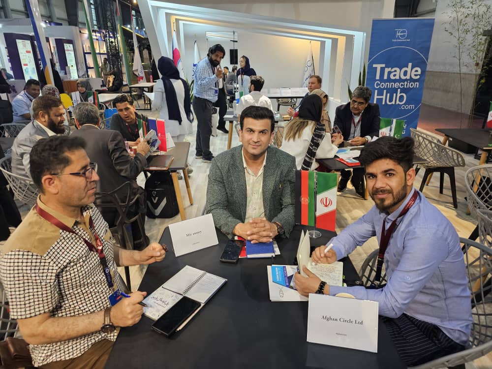 Afghan Circle Ltd. representatives at a trade exhibition with company table signage.